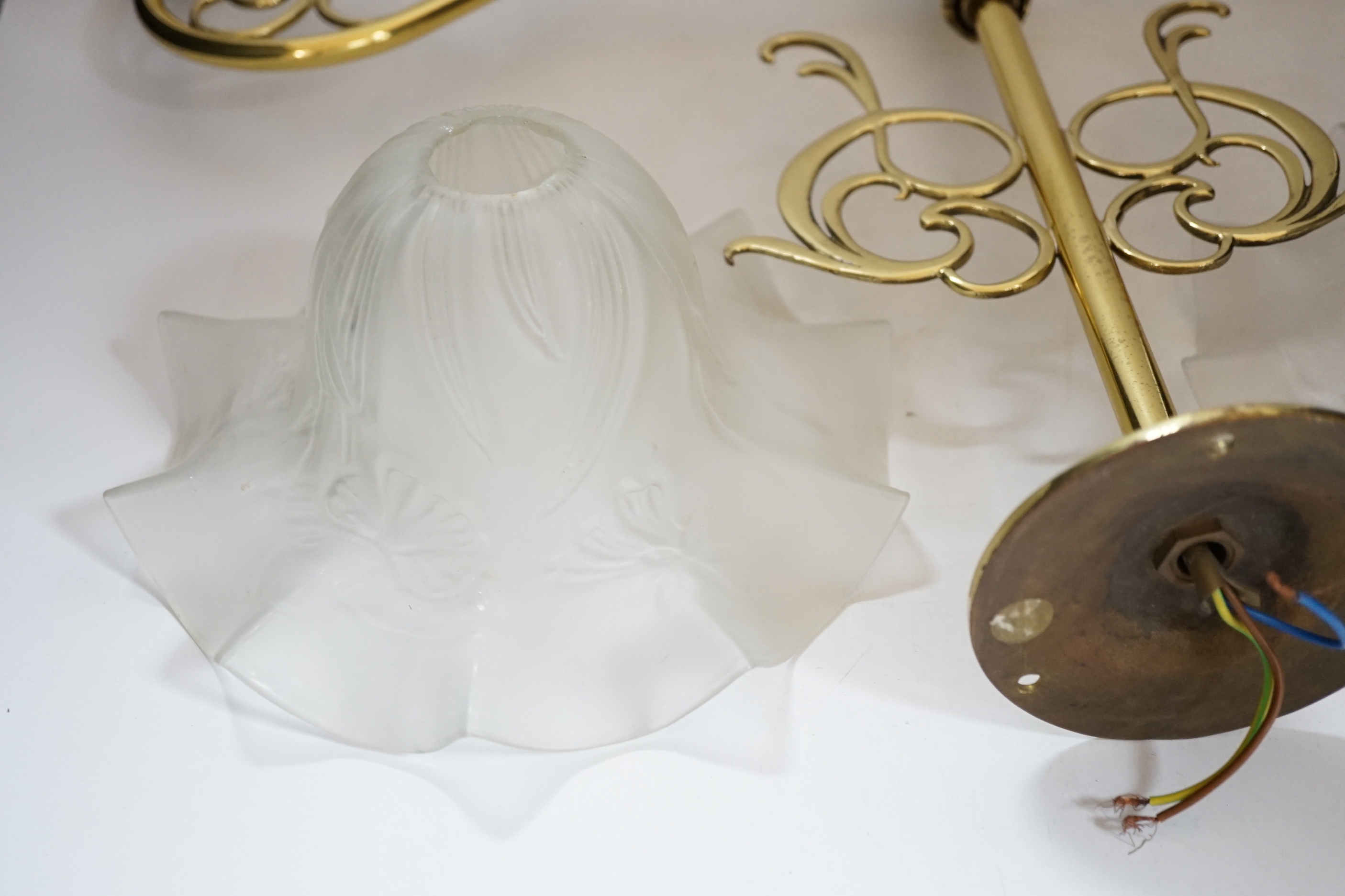 A brass pendant light and two opaque glass frilled shades, 60cm wide
